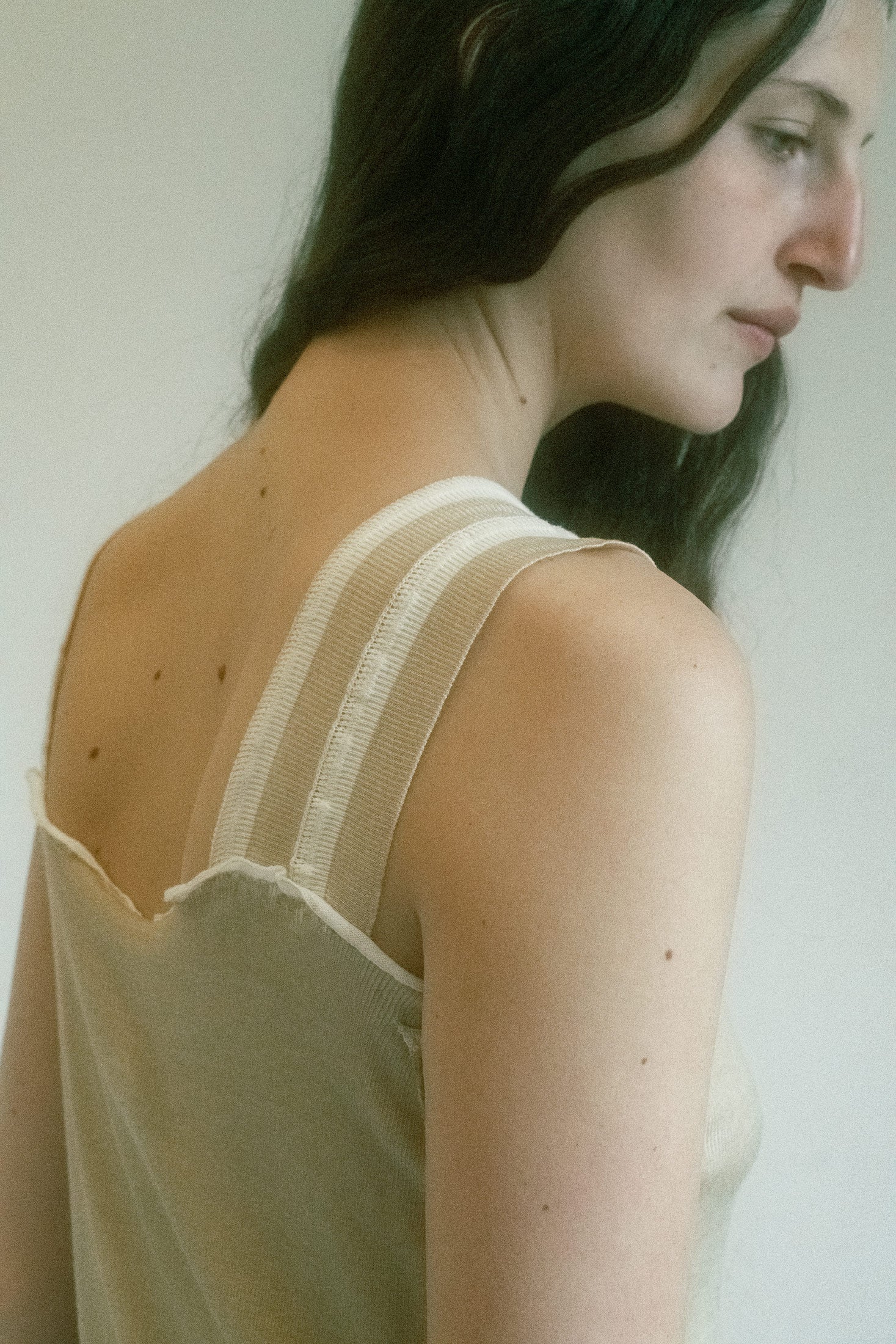 Straight across the top like a line drawn with intent, it’s held in place by thick ribbon straps, each one adorned with a contrasted stripe—a subtle flex, like a racing stripe on something otherwise still.
