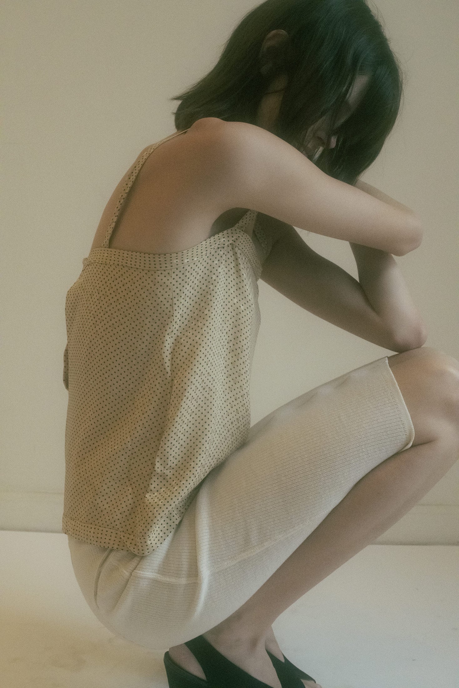 Featuring an iridescent polka dot print, this tank top catches the light with a subtle, mesmerizing glow, adding a touch of mystery to its otherwise simple silhouette.