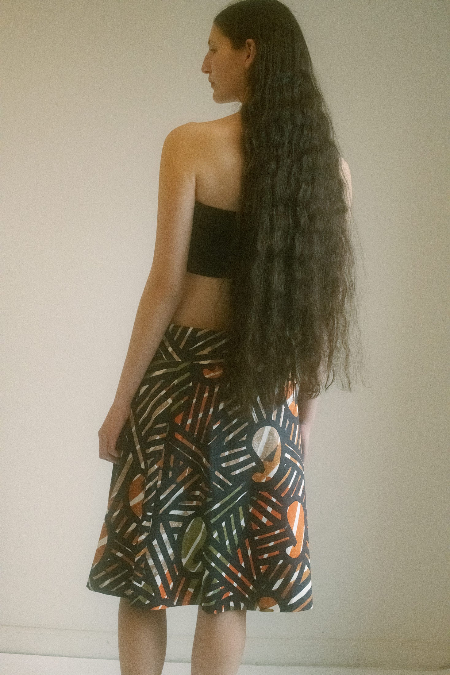 The geometric print? A brilliant play of colors. Orange—sharp, electric—meets green, cool and calculated, while black slashes through the canvas like a declaration of intent.