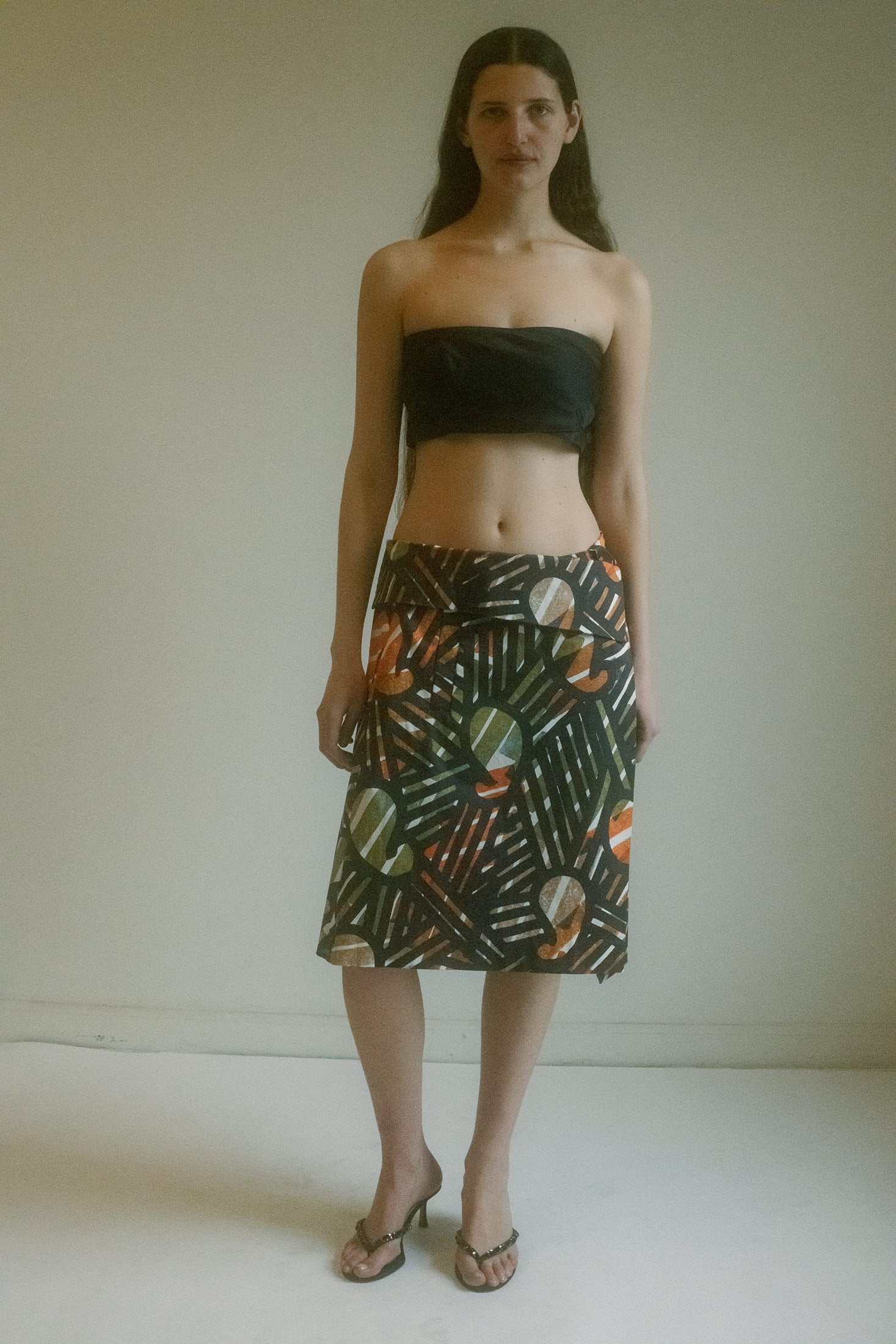 The Vintage Issey Miyake Knee-Length Wrap Skirt—a swirling kaleidoscope of orange, green, and black, an explosion of geometric chaos bound by the quiet elegance of Miyake’s genius.