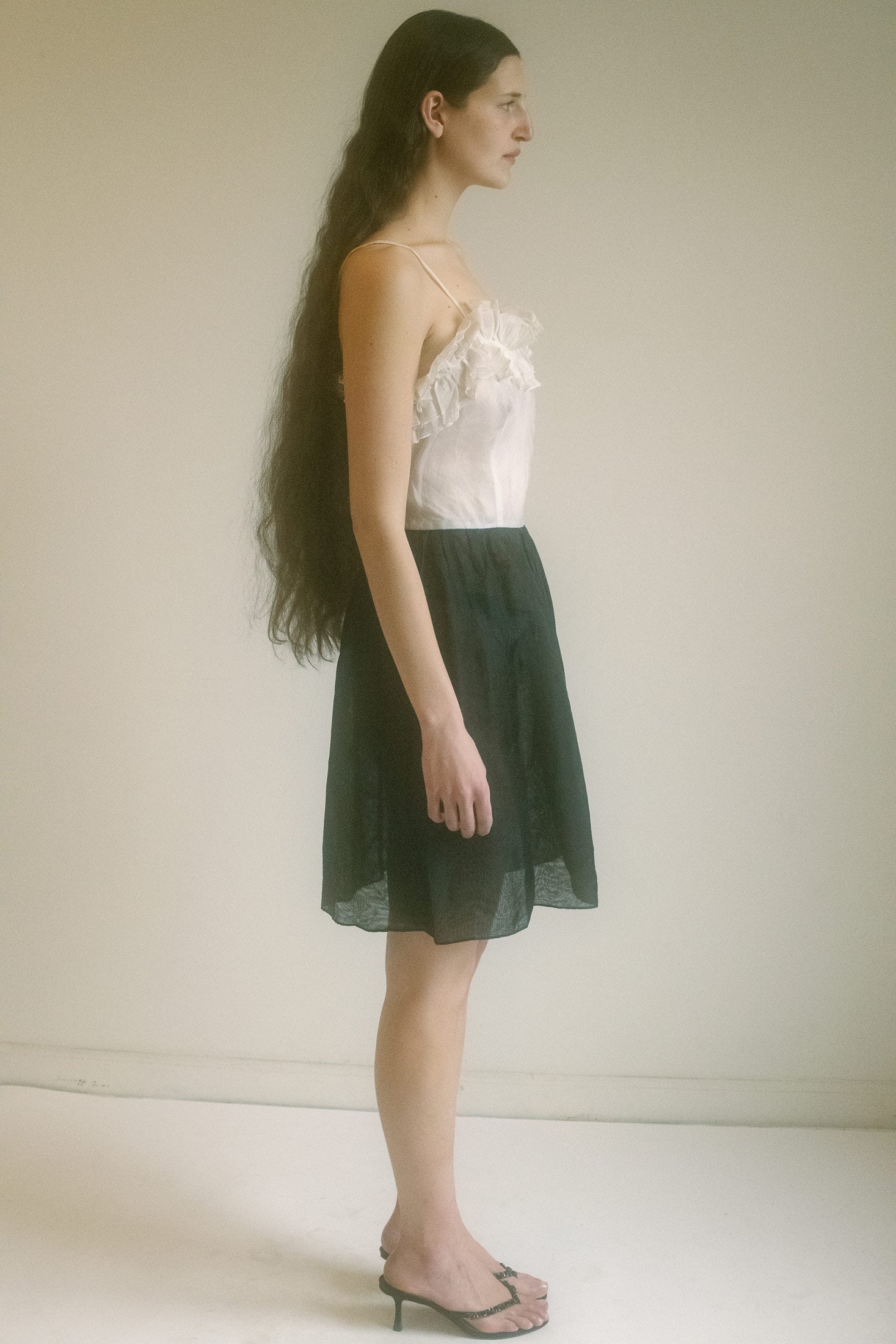 The top—white as moonlight, almost ethereal in its transparency—has ruffles that gently frame the chest, flattering every curve with a soft, feminine touch.