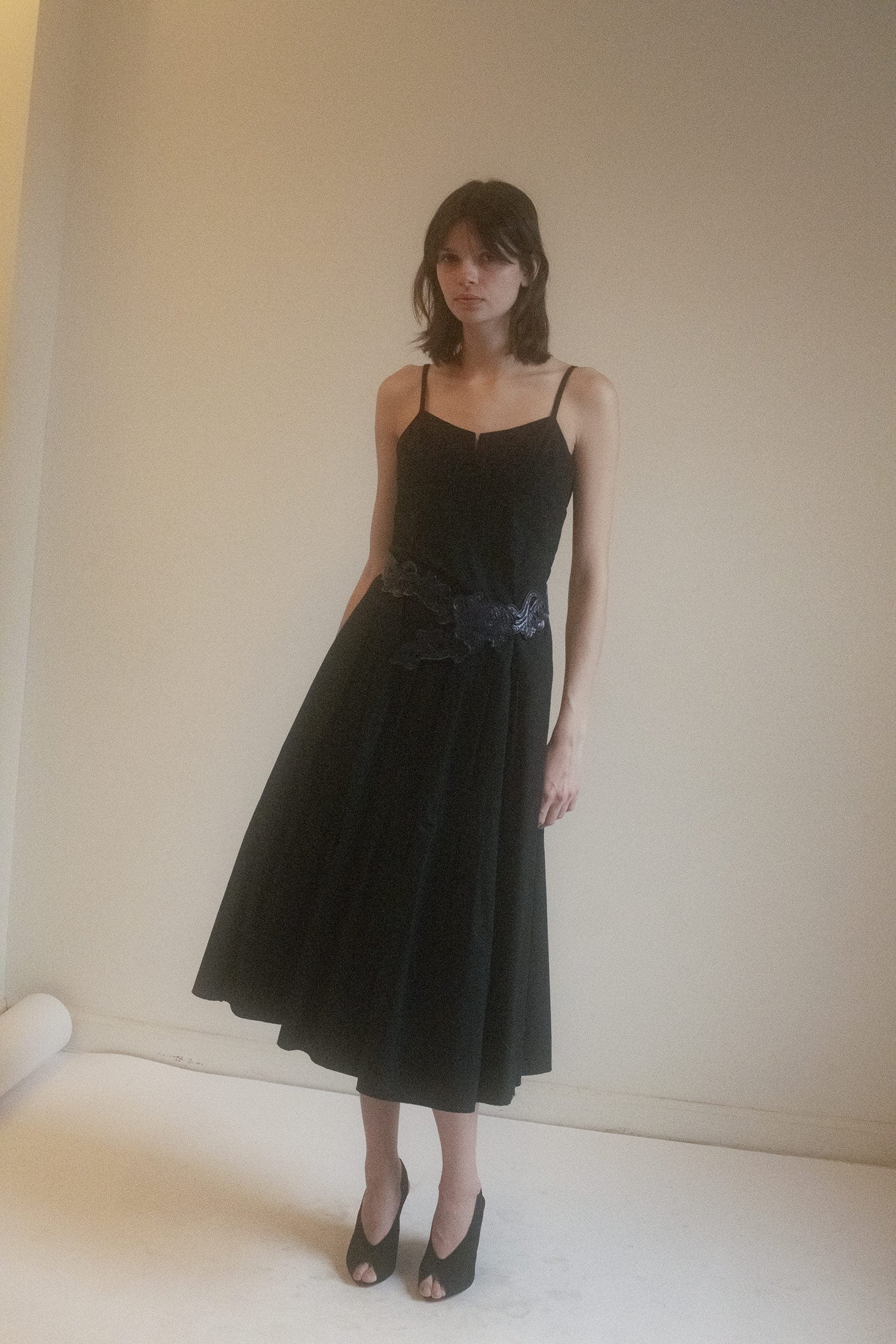 Crafted from black cotton with a subtle, breathable weight, its mid-length hem and cascading tiers lend motion to stillness.