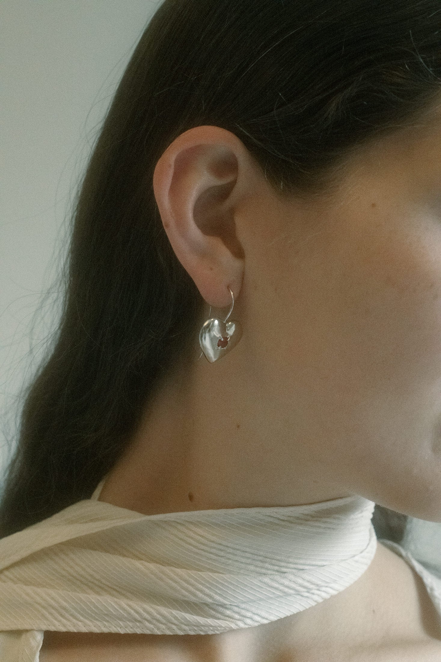 Crafted from silver-tone brass, each earring descends in a slink of cup chain, glass crystals catching the light.