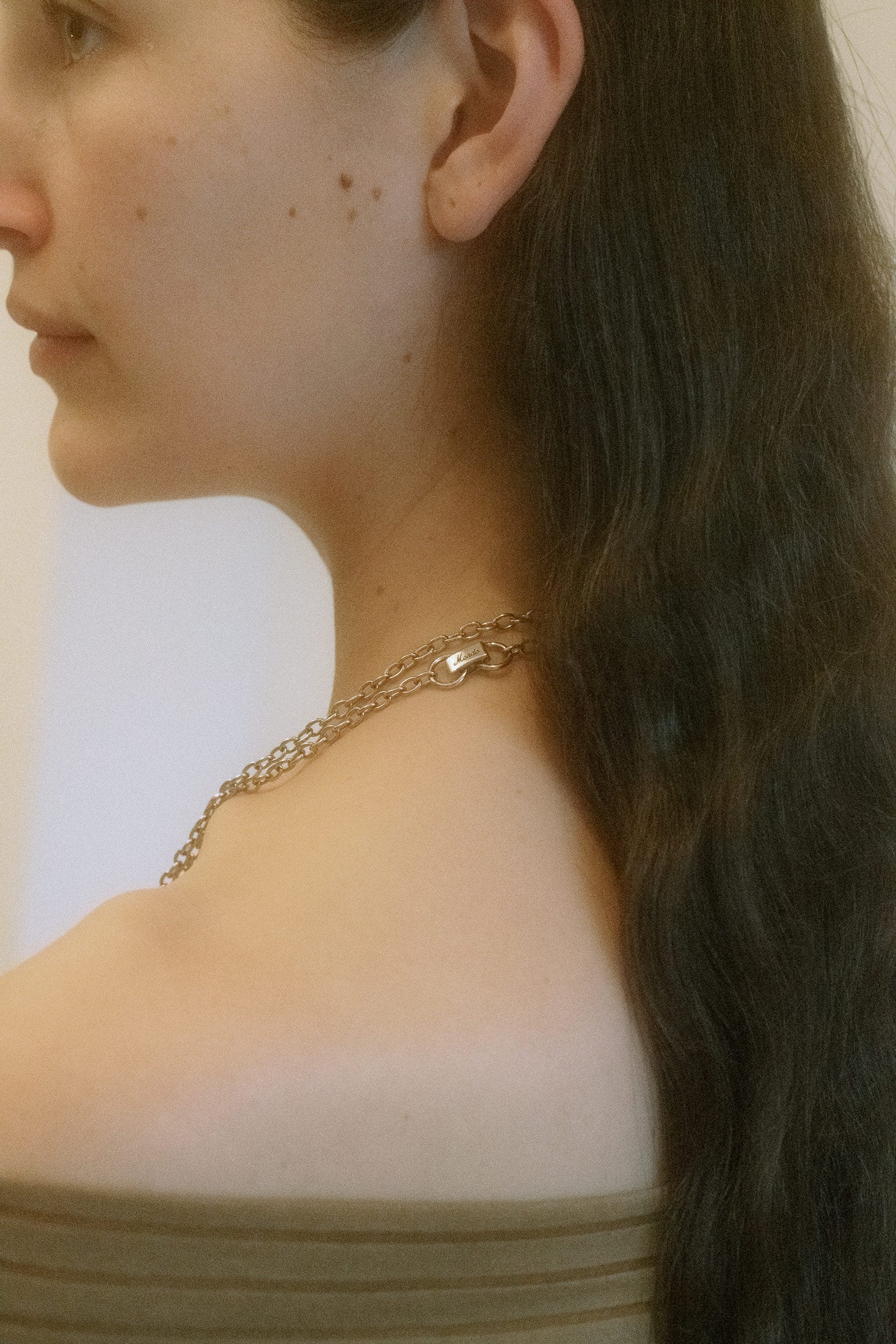 The hammered heart charm, with its organic texture, radiates an understated elegance, while the centered emerald-cut red gem offers a daring pop of color.