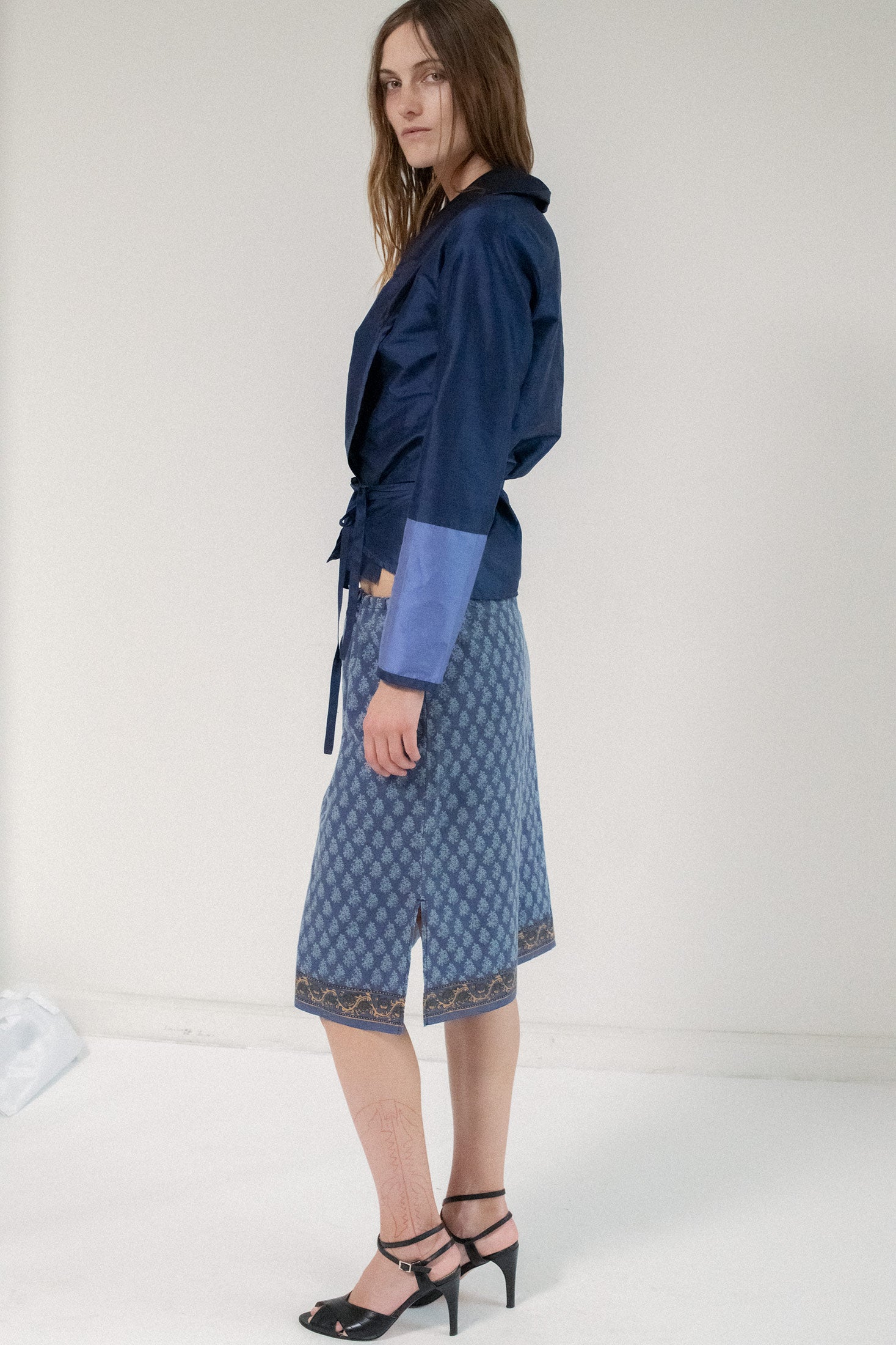 The waist ties gently, cinching the look with purpose, while the extended collar adds a sculptural touch—elegant, effortless, and utterly dynamic.