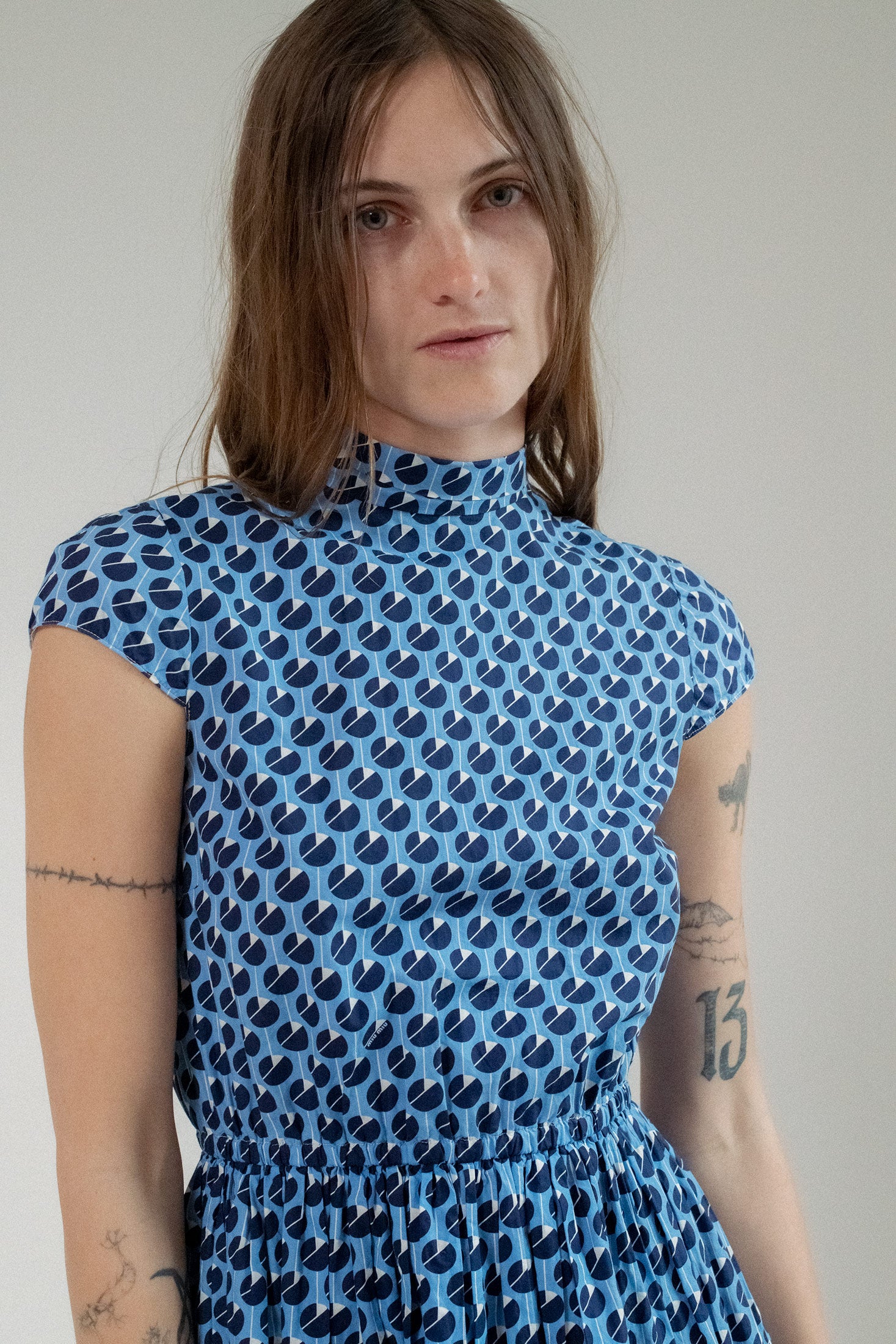 The cap sleeves glide gracefully, creating a contrast between the sharp angles of the design and the flow of the fabric.