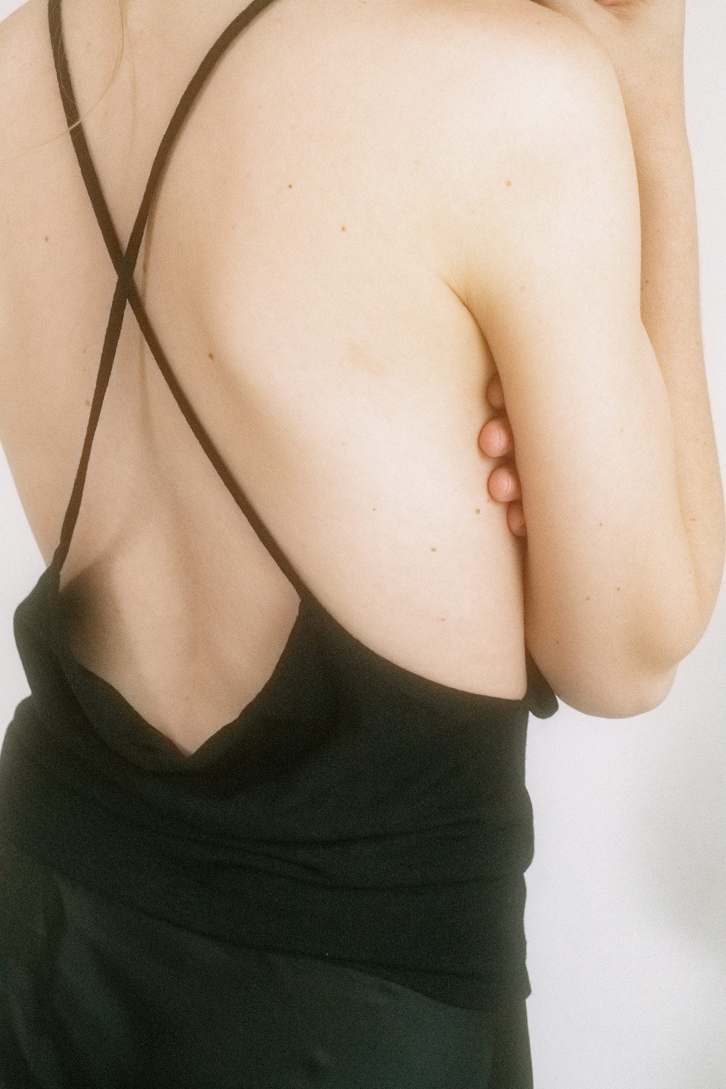 Thin straps frame the shoulders before giving way to an open back with an artful twist—like something slipped on after midnight and never taken off.