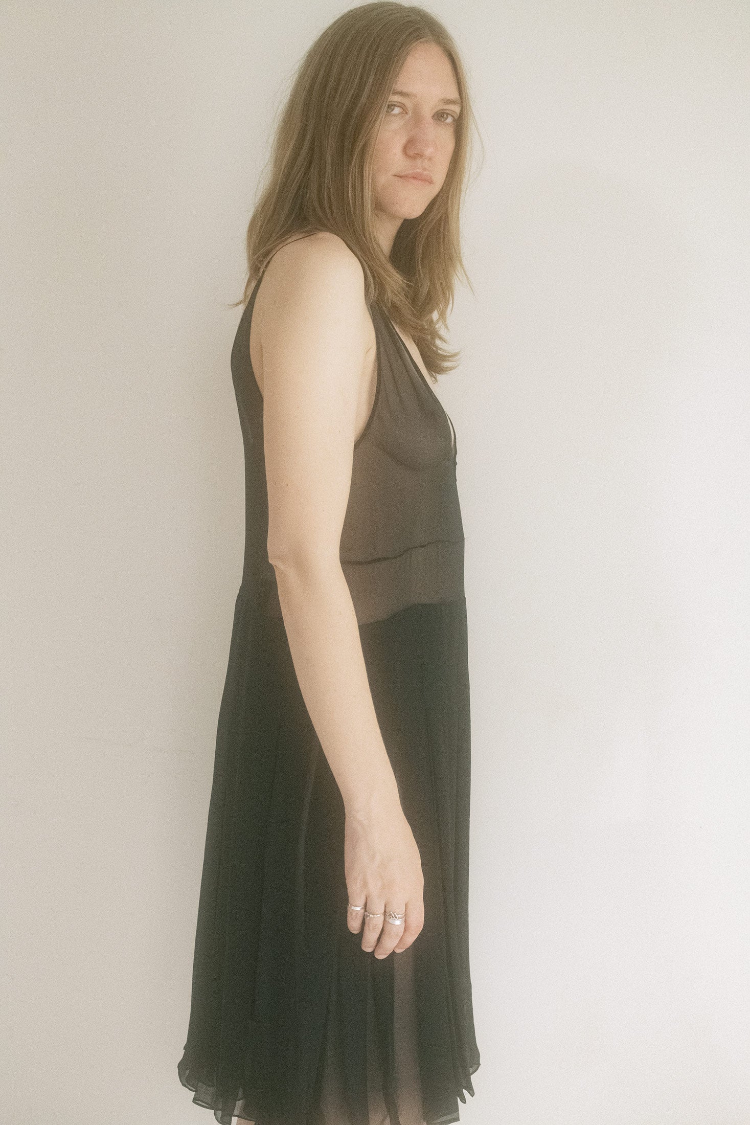 Thin straps trace delicate lines over the shoulders, while the subtly pleated skirt catches every whispered movement, hinting at mystery with every sway.