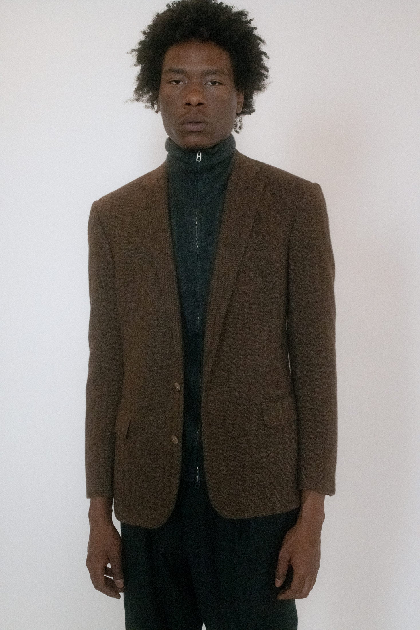 The two front pockets, button closure, and single-breasted present as orderly on the surface, but there’s a mischievous current underneath.