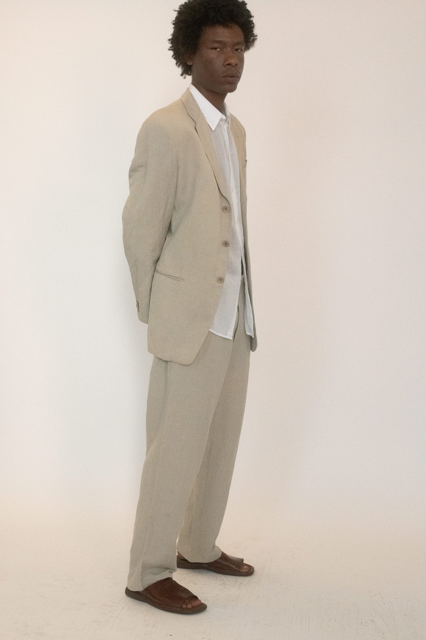 A single button closure and zip fly anchor the waist, while front pleats open into a relaxed silhouette that feels precise without being rigid.