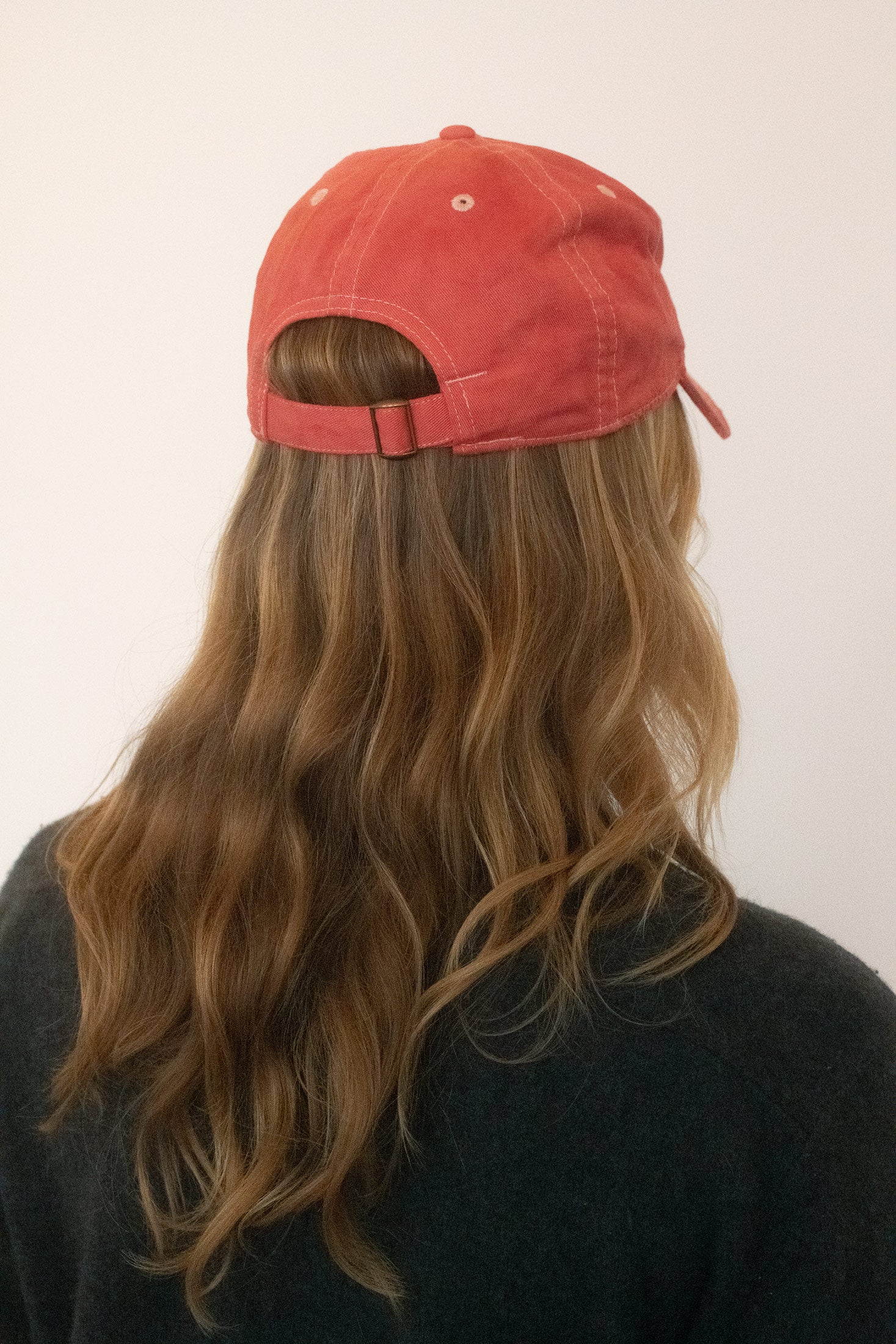 At the back, an adjustable strap keeps the fit easy, while the front is marked with custom embroidery.