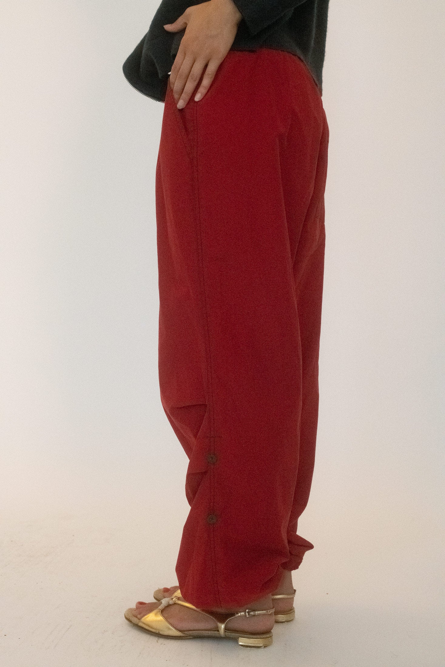 The exposed elastic waistband and gathered ankles frame the body with precision, pulling tension into the silhouette like a scene paused mid action.