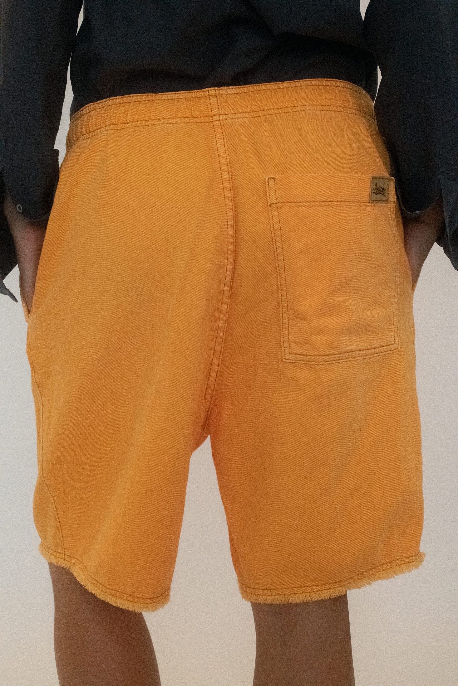 A raw edge hem leaves them deliberately undone, a trace of rebellion at the finish.