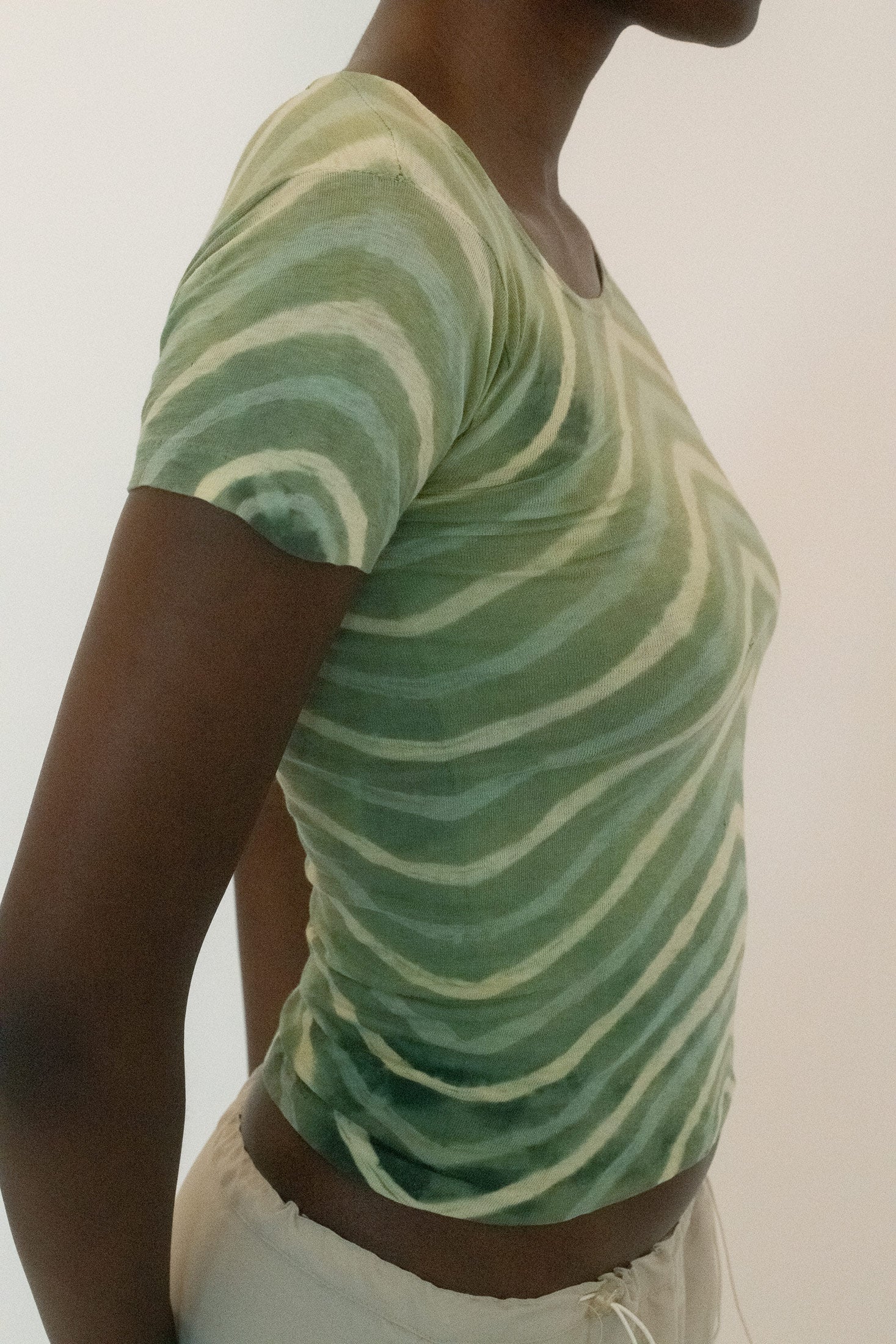 Cut in a classic fitted shape, its patterned in striped green, the kind of understated palette that lingers, more mood than statement.