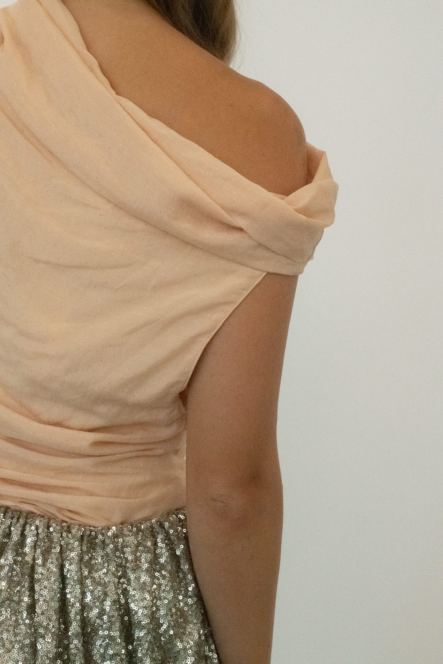 The delicately draped neckline softens the structure, a fluid gesture that frames without forcing.