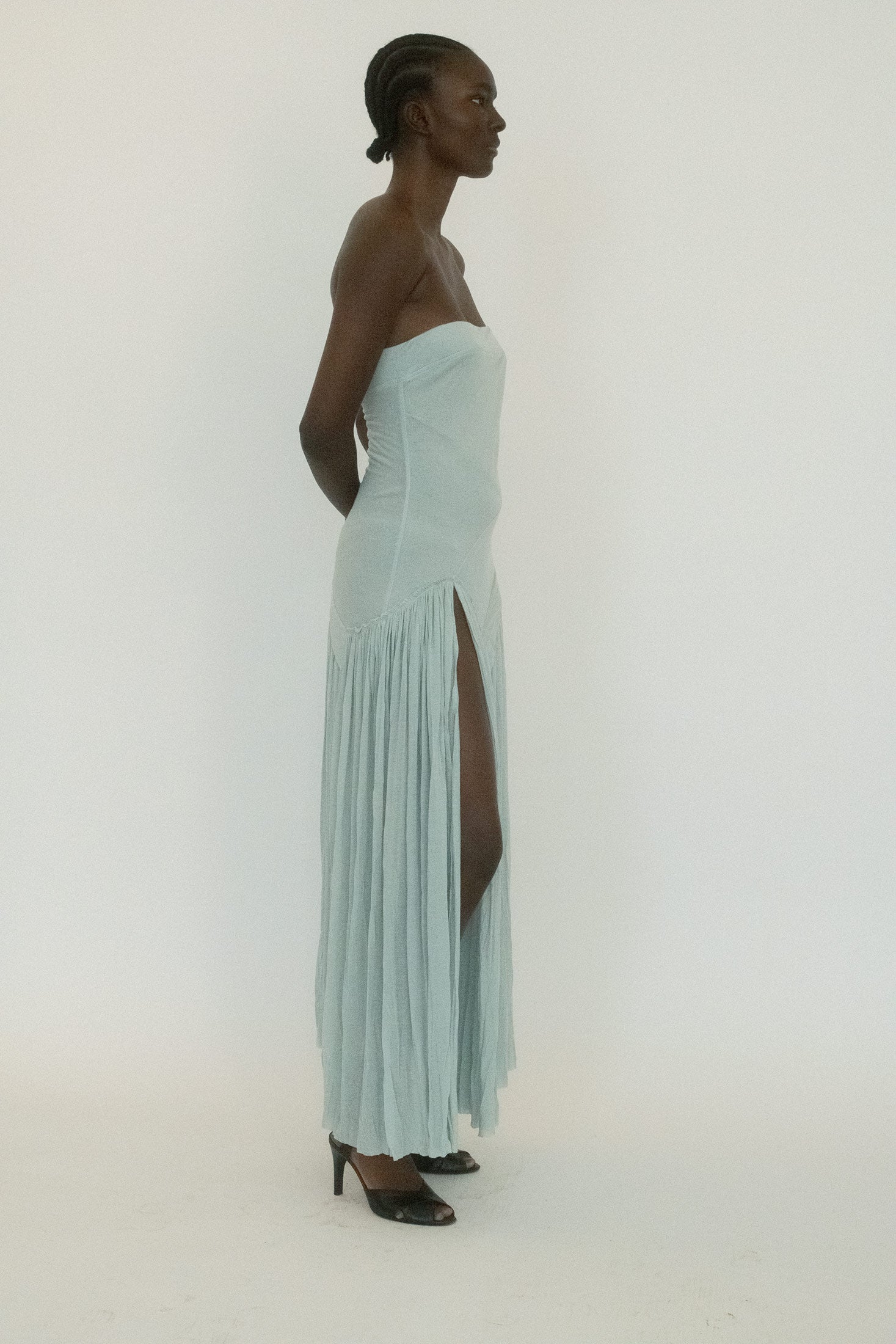 Crafted in soft jersey, it drapes close before giving way to a leg slit, a flash of drama that breaks the column like facade of the dress.