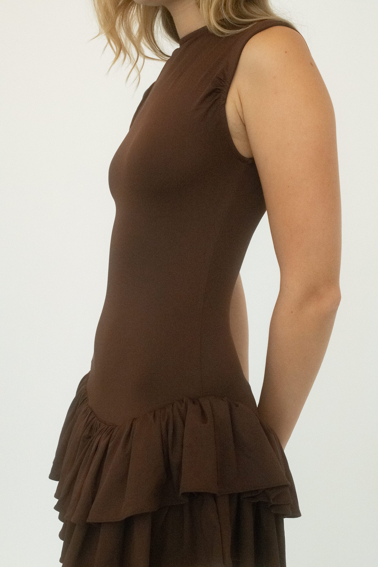Below, a double-layered ruched skirt brings movement and complexity, the fabric gathering in deliberate folds that catch the light with each step.