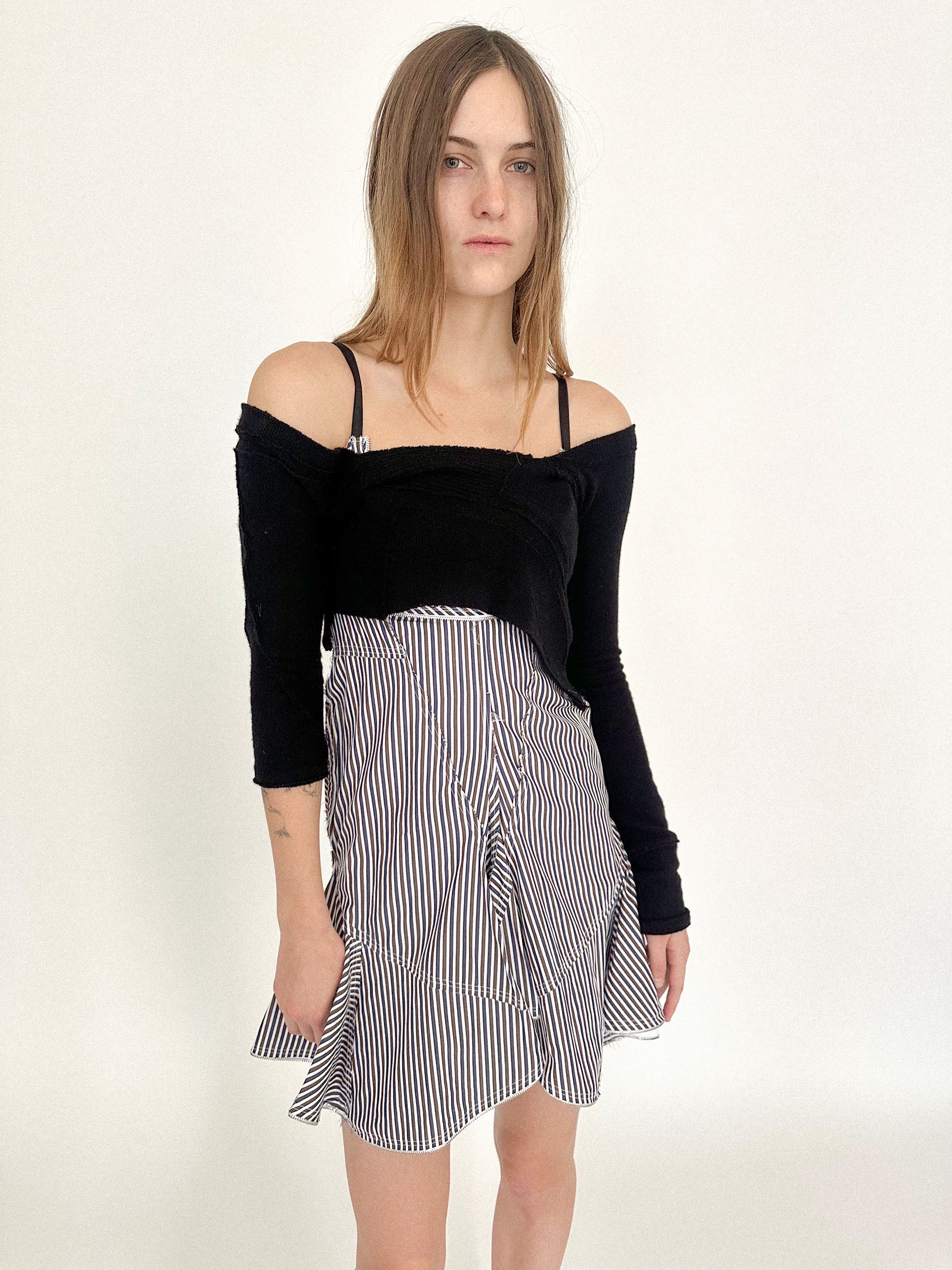 A scooped V-neck opens the frame, while the uneven hem gives it motion - like a garment caught mid-scene.