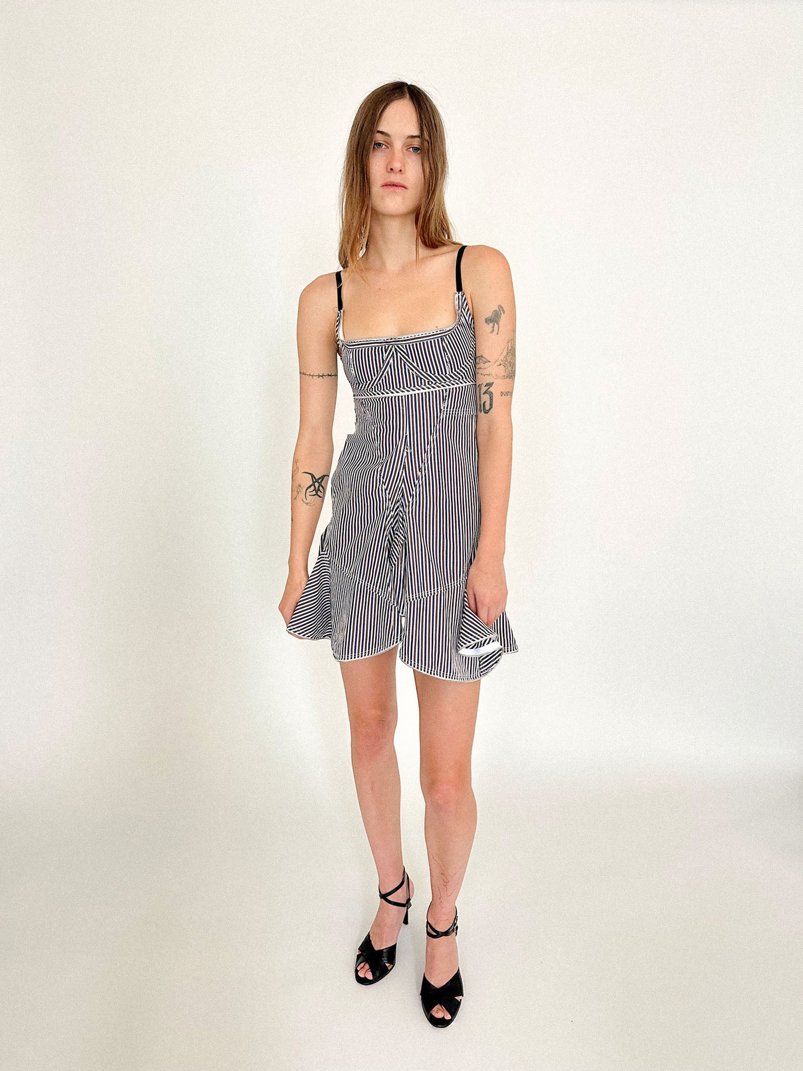 Hook-and-eye closures fasten at the open back, a balance of exposure and restraint.