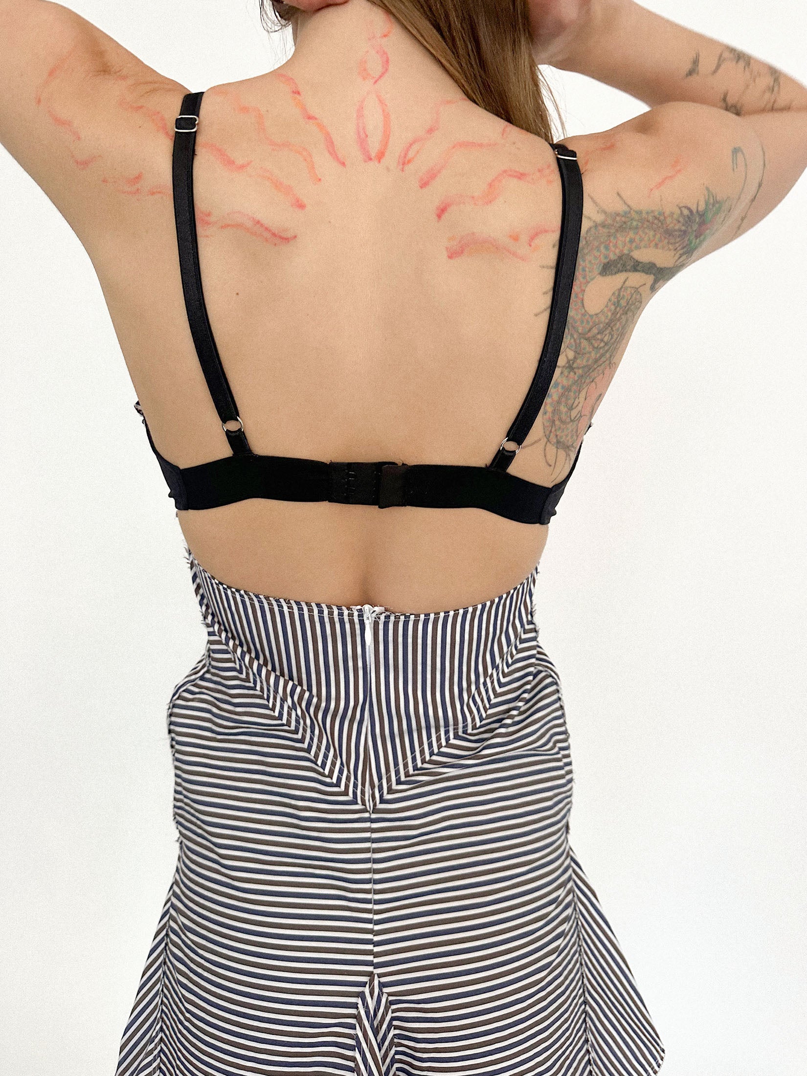 Below, a ruffled skirt breaks the line, softening the discipline of the pinstripes with a flicker of motion.