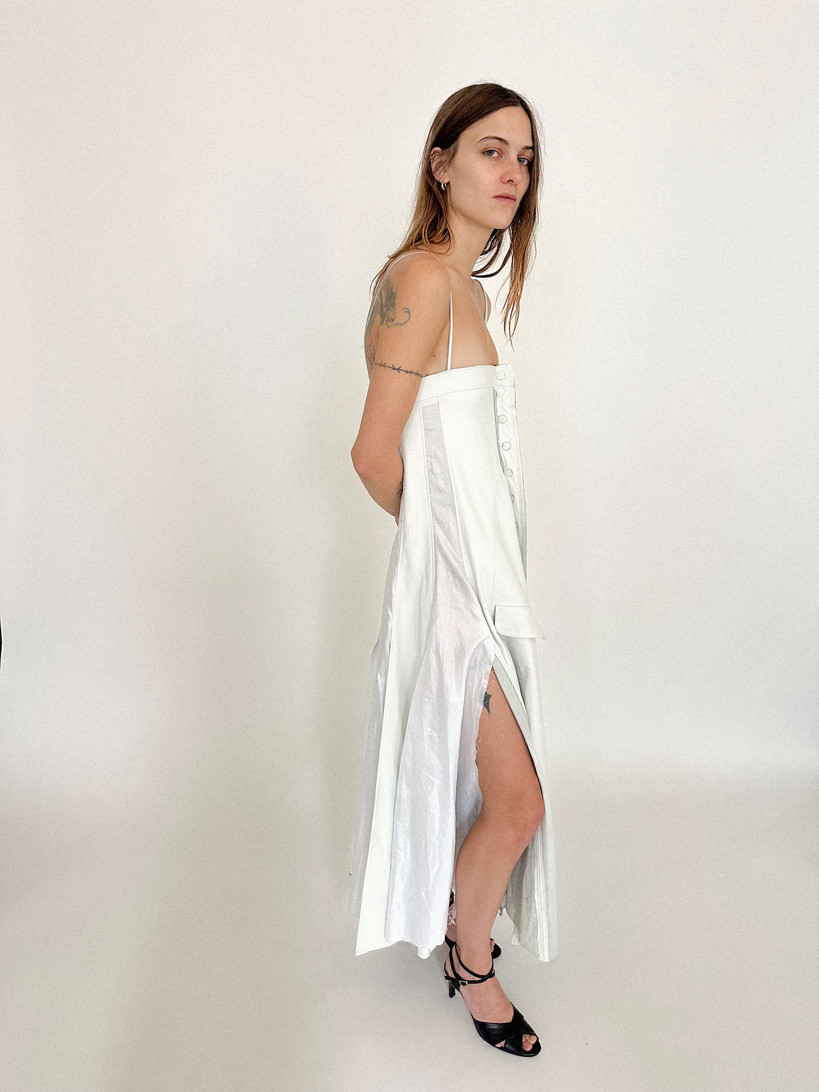 Smooth panels of white leather give way to slitted silk inserts that move like air against structure, an interplay of restriction and release.