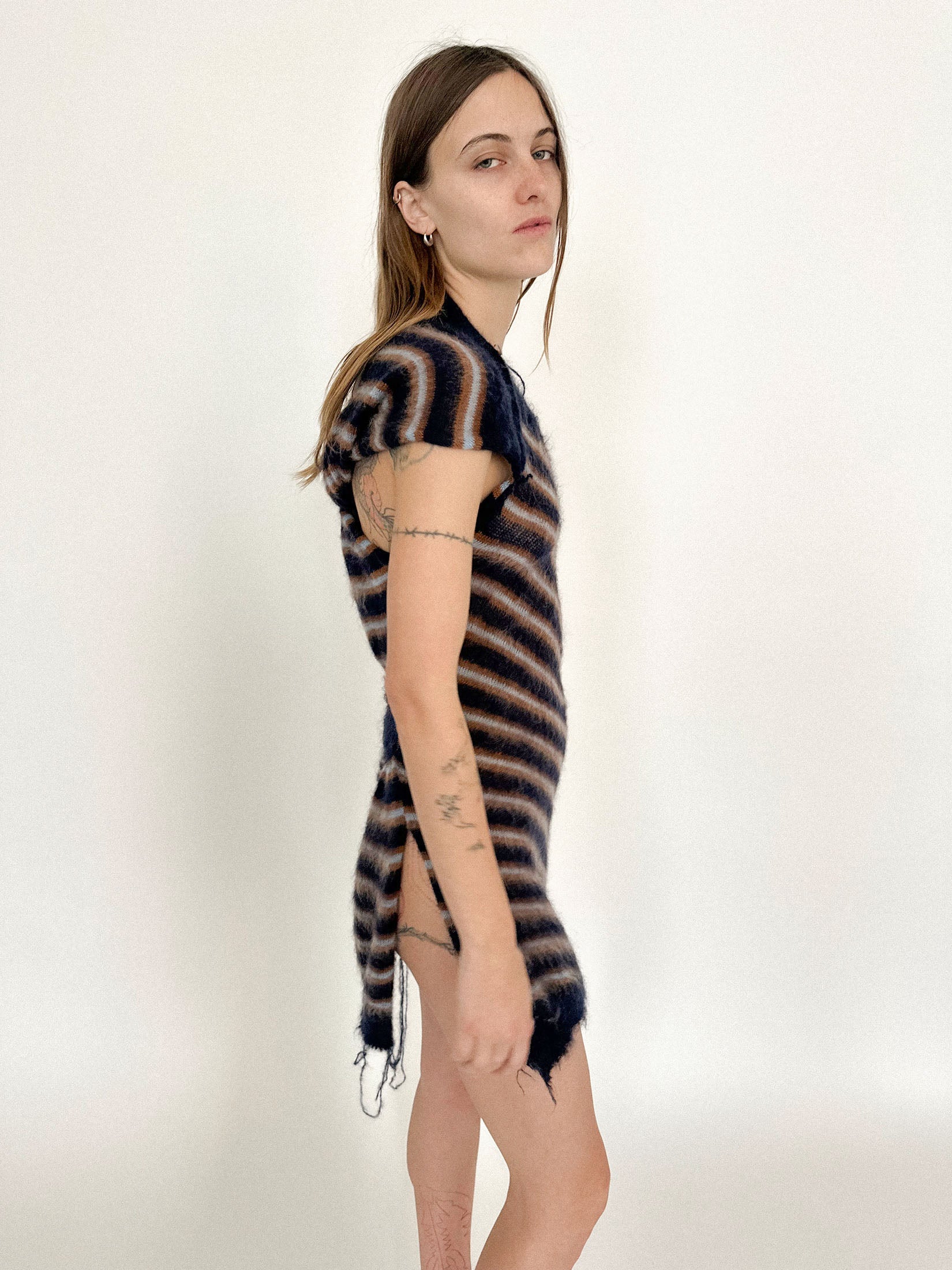 A side slit cuts through the striped knit, breaking its rhythm just enough to feel deliberate.