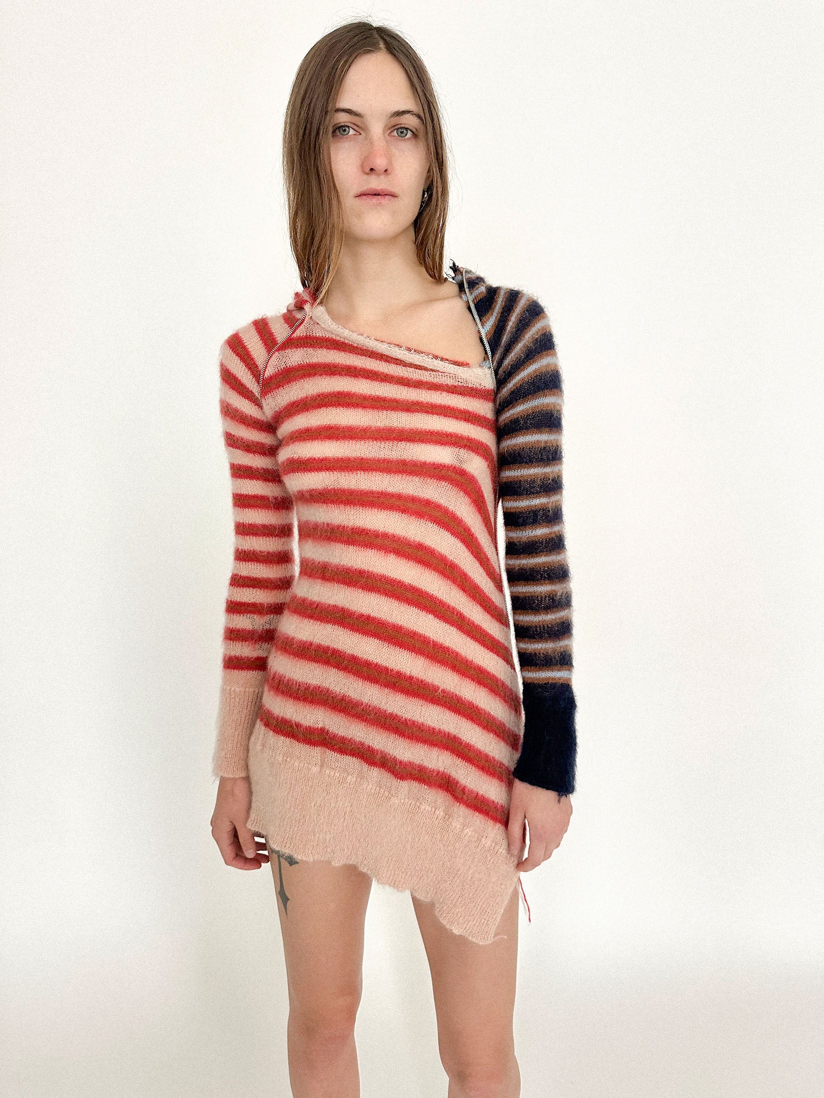 A mohair hooded tunic by Talia Byre, spun in red stripes with one sleeve breaking rank in blue - a deliberate interruption.