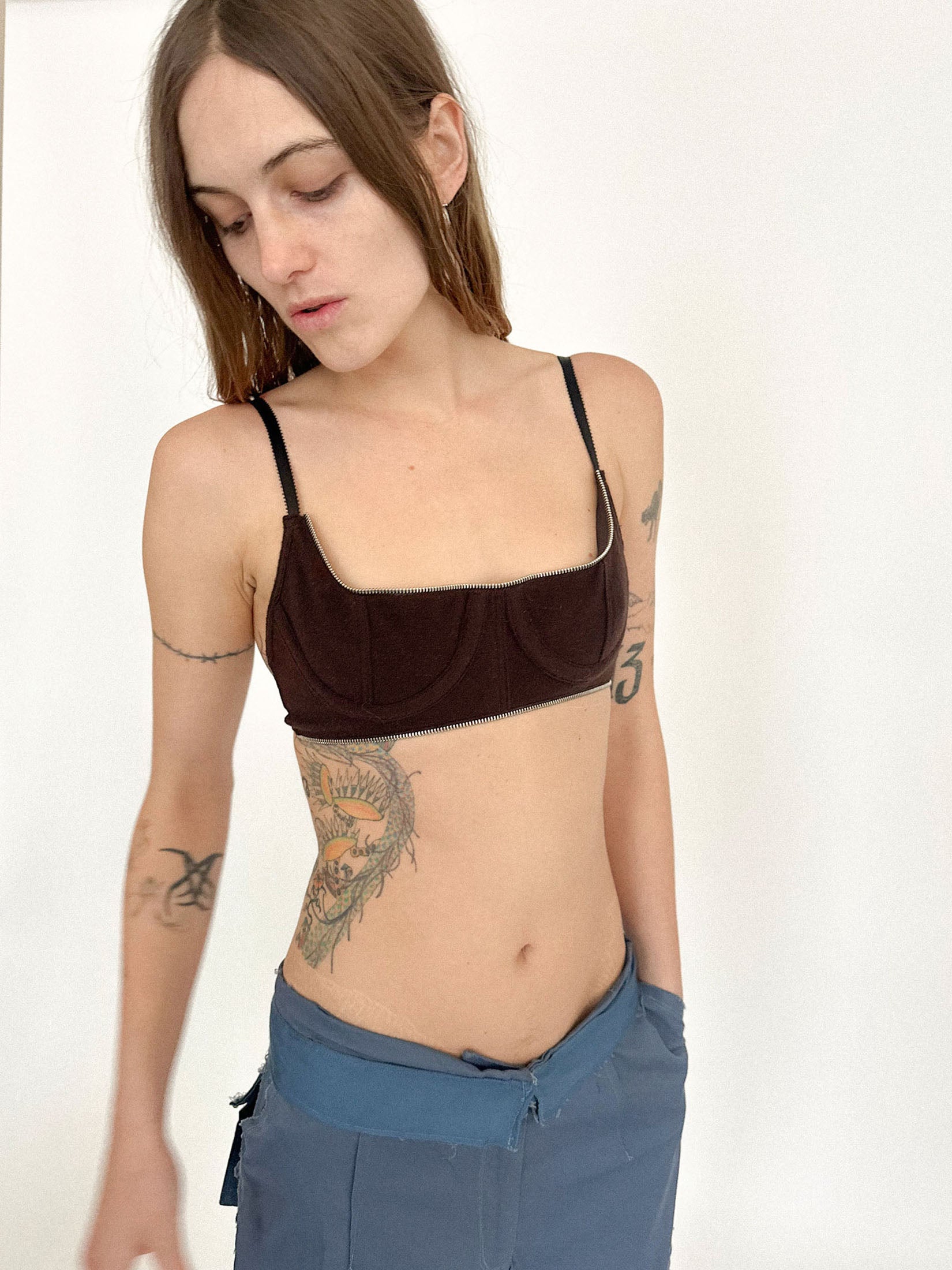 Zippered detailing traces the edge, catching the light like a whispered warning, turning texture into tension.