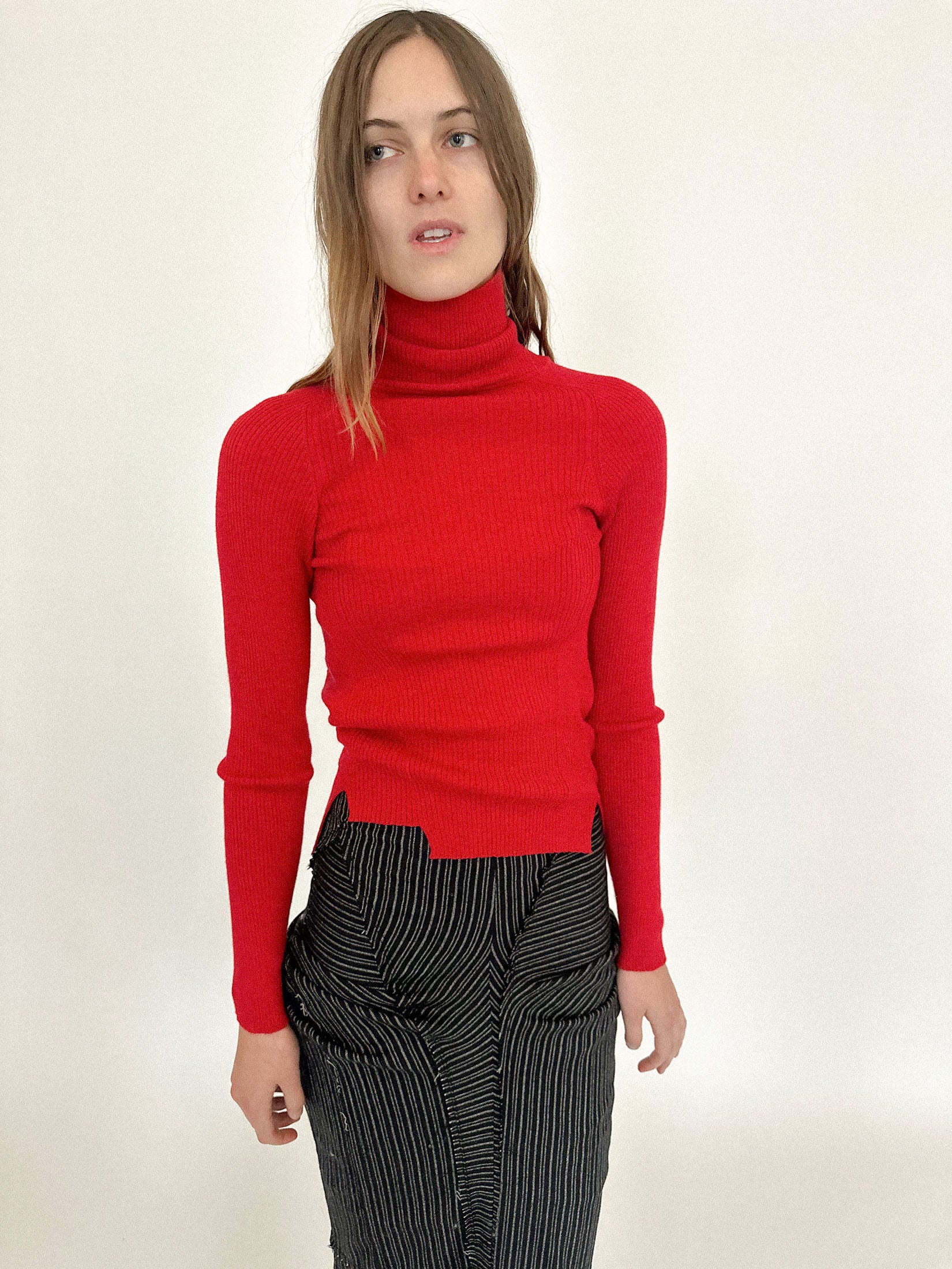 A rib knit turtleneck top by Talia Byre, rendered in an arresting red that feels more like a statement than a color.