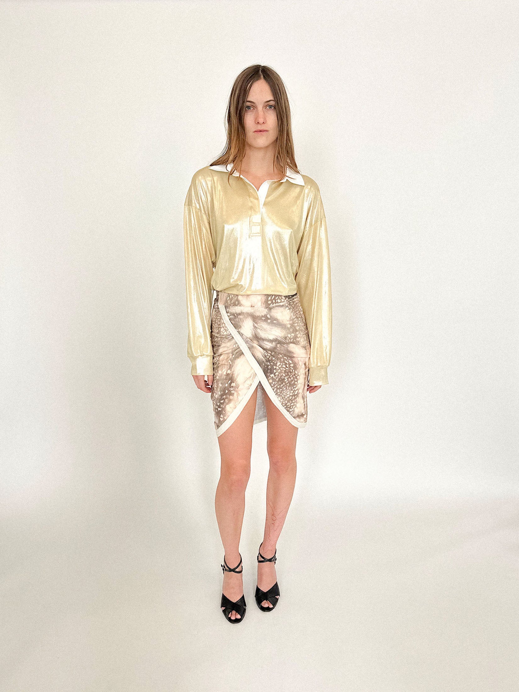 A rugby shirt by Talia Byre, cut loose in gold jersey that gleams like a provocation under dim light.