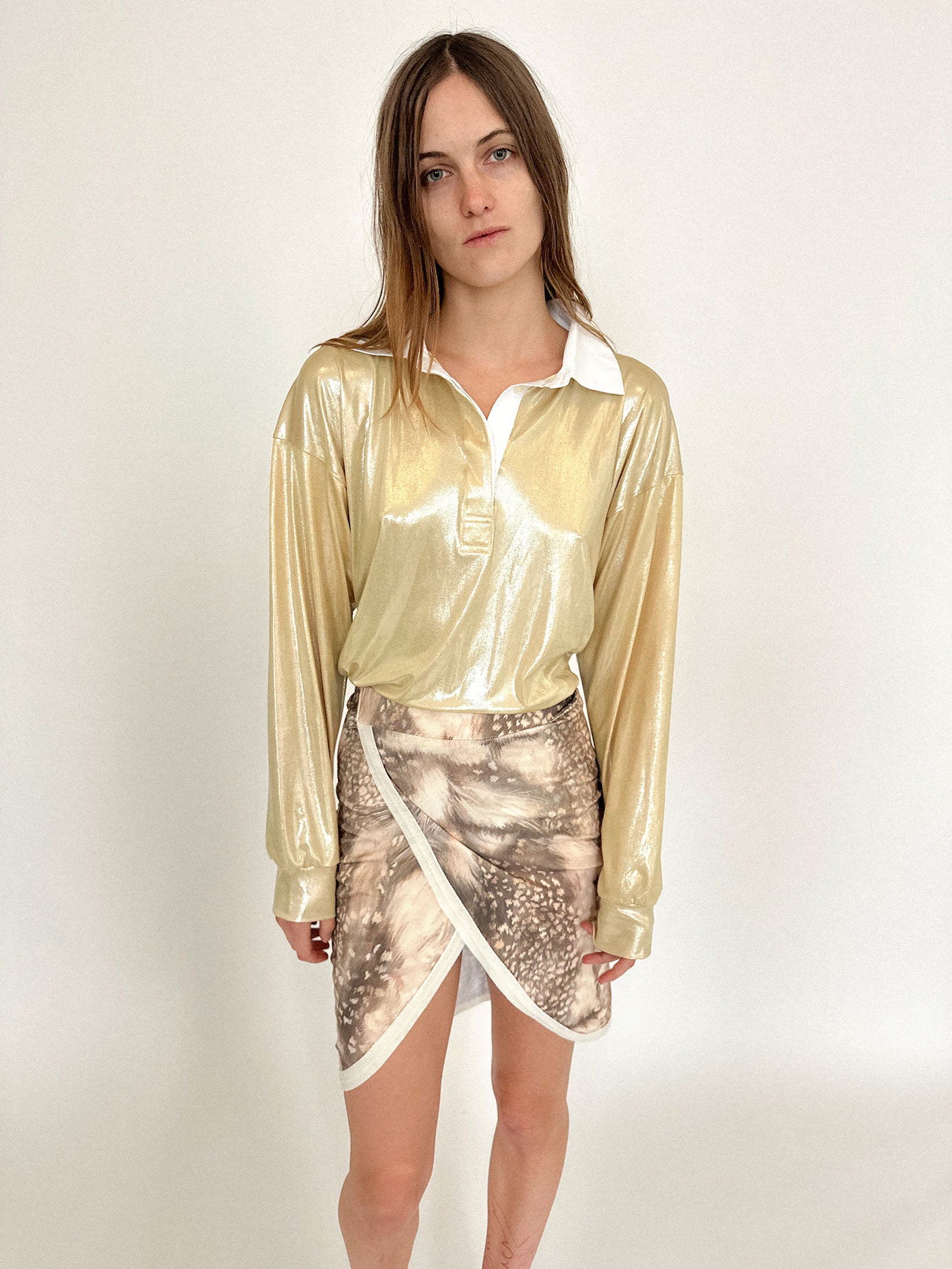 A rugby shirt by Talia Byre, cut loose in gold jersey that gleams like a provocation under dim light.