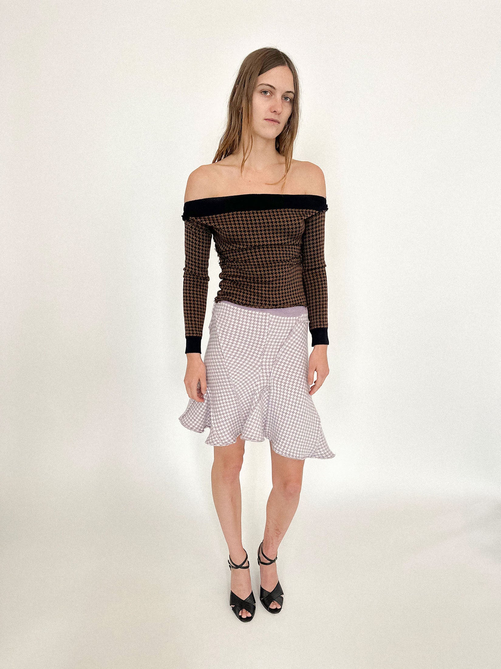 Slight ruching gathers the waist, hinting at form without confinement, while black accents trace the neckline and wrists, framing the gesture of skin revealed.