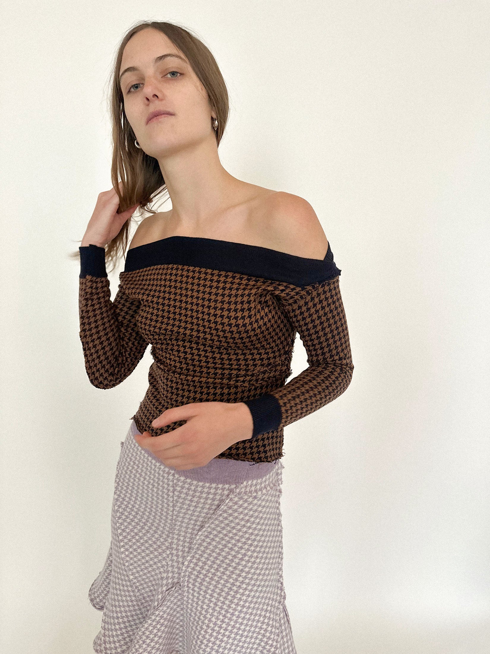 The houndstooth print, brown and black in contrast, moves like static, sharp yet familiar.