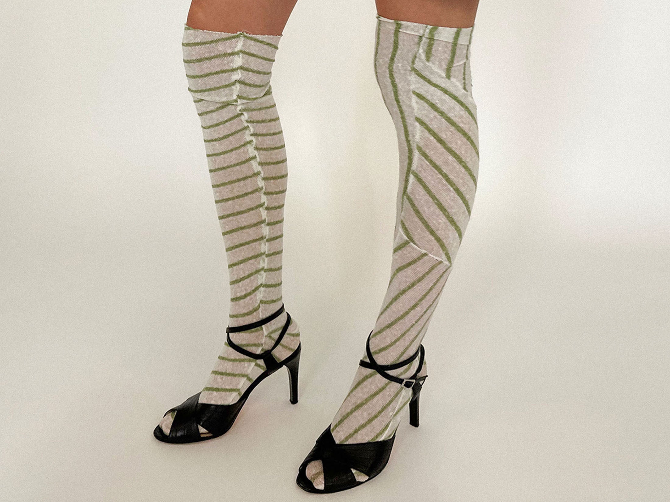Knit socks by Talia Byre, designed with swirling green stripes that coil up the leg like smoke in motion.