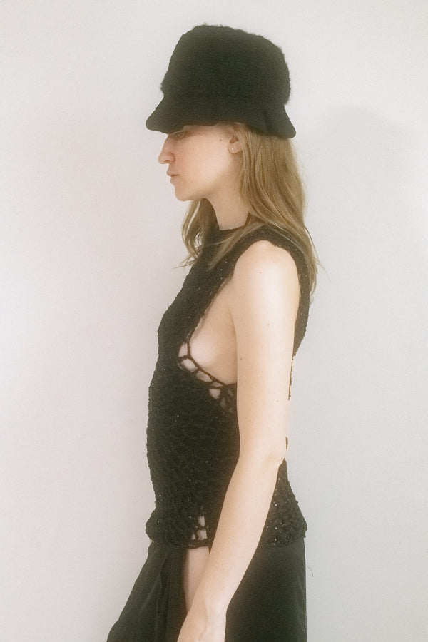 From the hands of Judy Turner comes a knit hat that tilts toward the surreal — crafted in New York with a small, sculpted brim and exaggerated volume that peaks into a quiet, fin-like crest. 