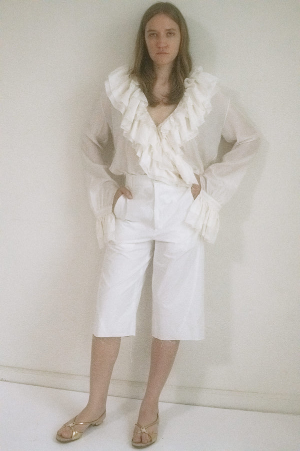Judy Turner’s high-waisted elongated shorts in crisp white carry a confident tension, where sleek tailoring meets subtle seduction. 