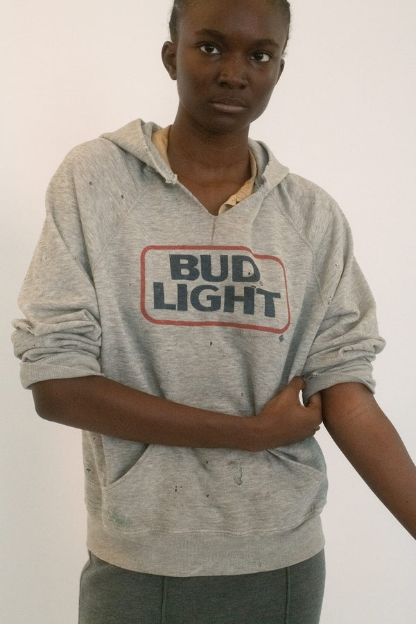A vintage Bud Light hoodie in heather grey, the kind of sweatshirt that wears its history in every soft edge and frayed seam.
