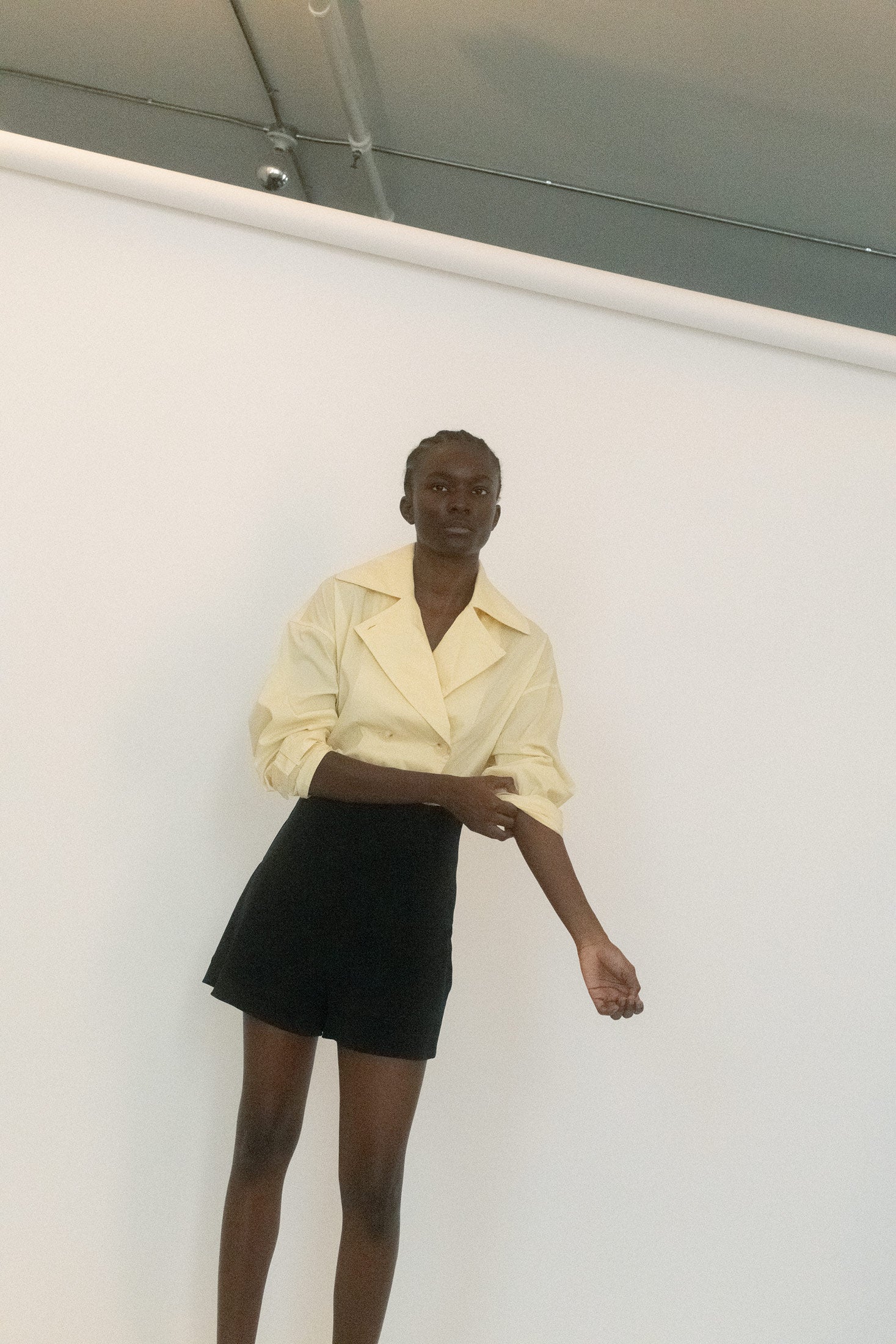 Classic trench details make their appearance: the broad collar framing the neck like a secret, the double-breasted buttons that beg to be undone one by one.