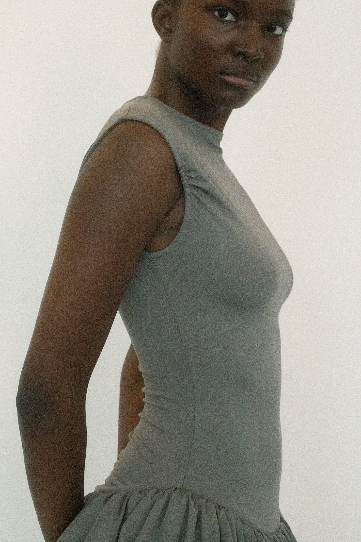Below, a double-layered ruched skirt brings movement and complexity, the fabric gathering in deliberate folds that catch the light with each step.