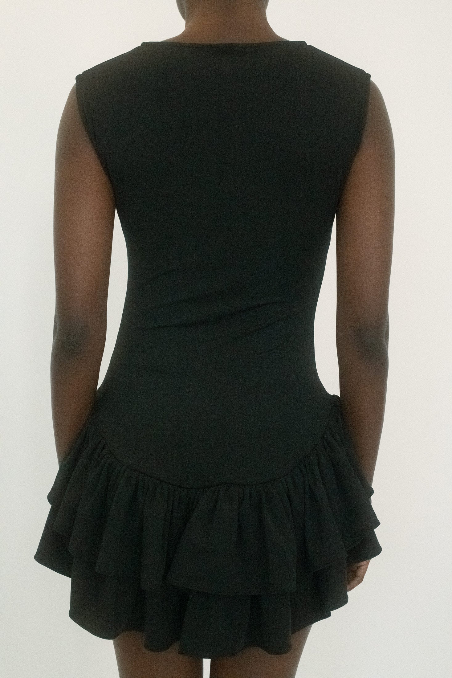 Below, a double-layered ruched skirt brings movement and complexity, the fabric gathering in deliberate folds that catch the light with each step.