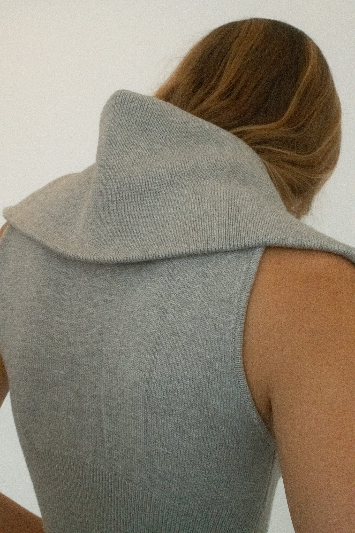 Rendered in a cool grey hue, the sleeveless cut and fitted silhouette keep it pared back, while the design itself hums with tension. 
