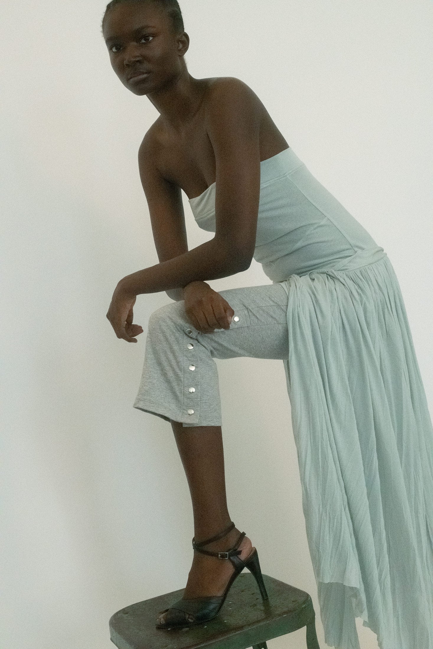Cut in heather grey, they sit close with a fitted silhouette and finish with silver snap detailing at the outer hem, a flash of hardware that reads more like punctuation than ornament.