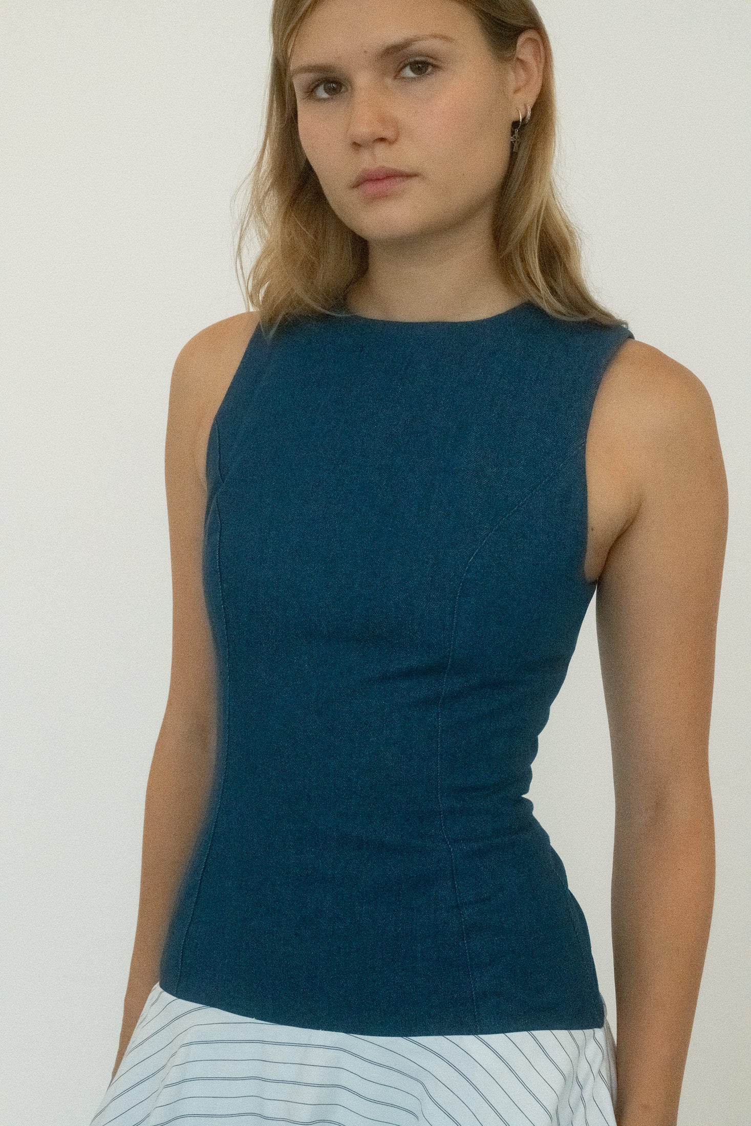 The denim bodice is sleeveless and fitted, tracing the torso with clean, deliberate lines. 