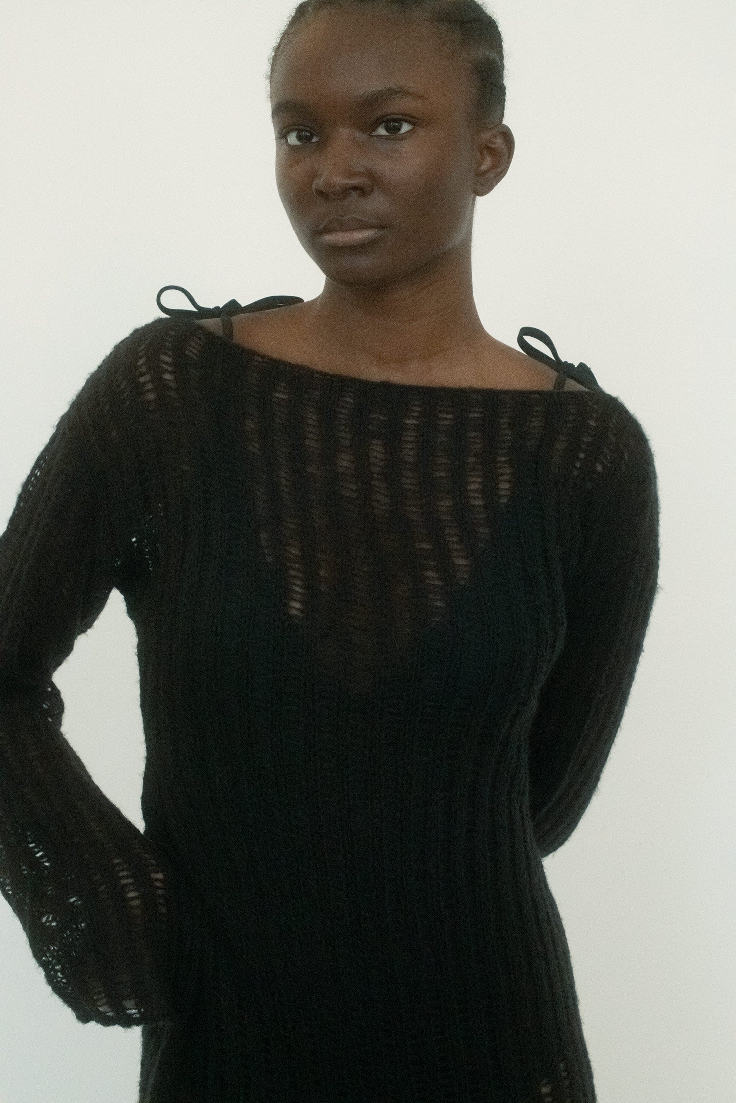 This full-length crochet dress is rendered in deep black, its weave thick yet semi-sheer, letting shadow and light play across the body.
