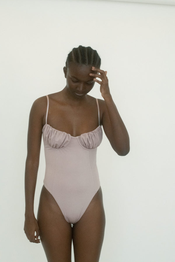 The Marcella One Piece from Belle the Label arrives in a shimmer of lilac - a hue that reads like a warning and an invitation all at once. 