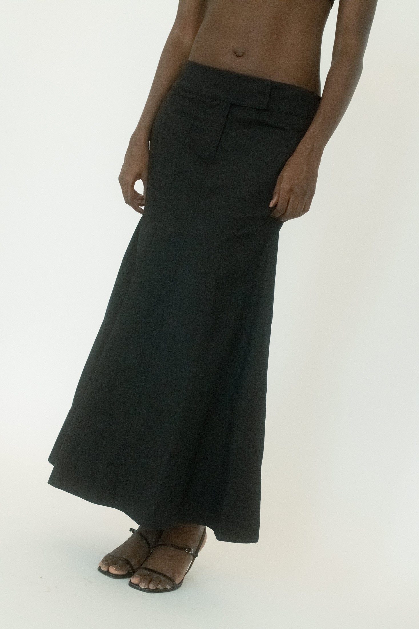 The paneled construction carves shape into the drape, while two-pocket styling adds a utilitarian nod without breaking the silhouette.