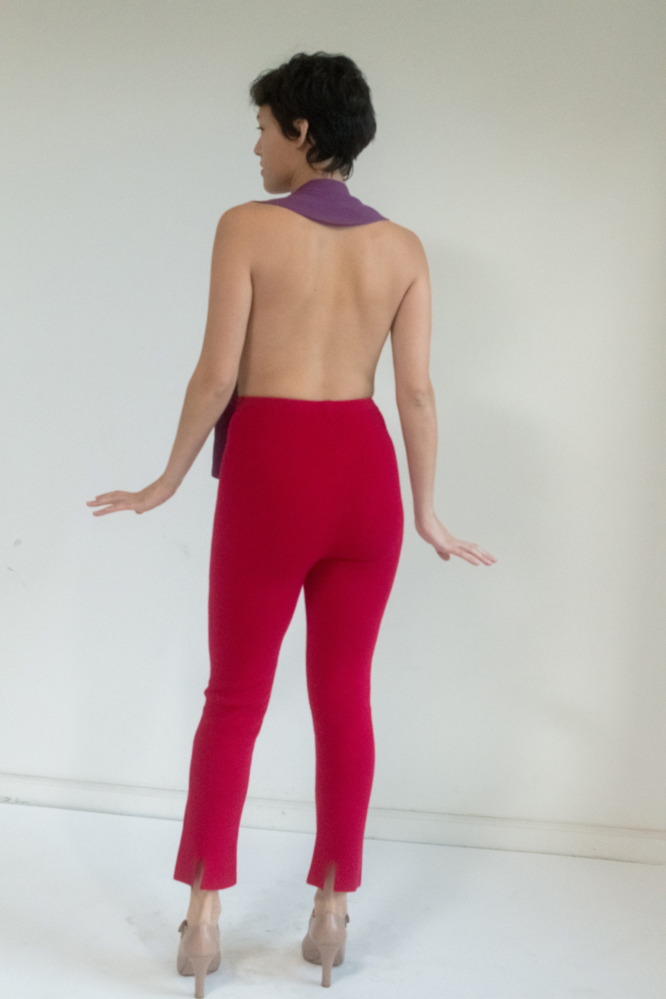 In magenta pink jersey, the fabric clings just enough, its softness laced with tension. The open back reveals more than it conceals. 