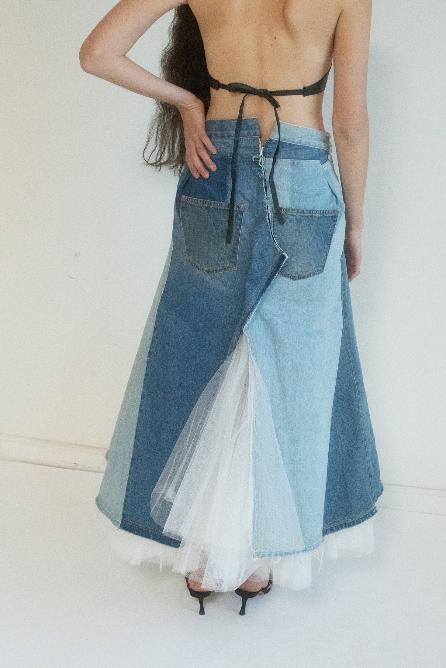 A masterpiece of contradiction: rugged patchwork denim, tough and raw, intertwined with a delicate white tulle insert at the center slit—soft, ethereal, and full of mystery.